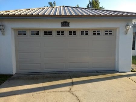Almond raised-panel garage door with short windows on a stucco home