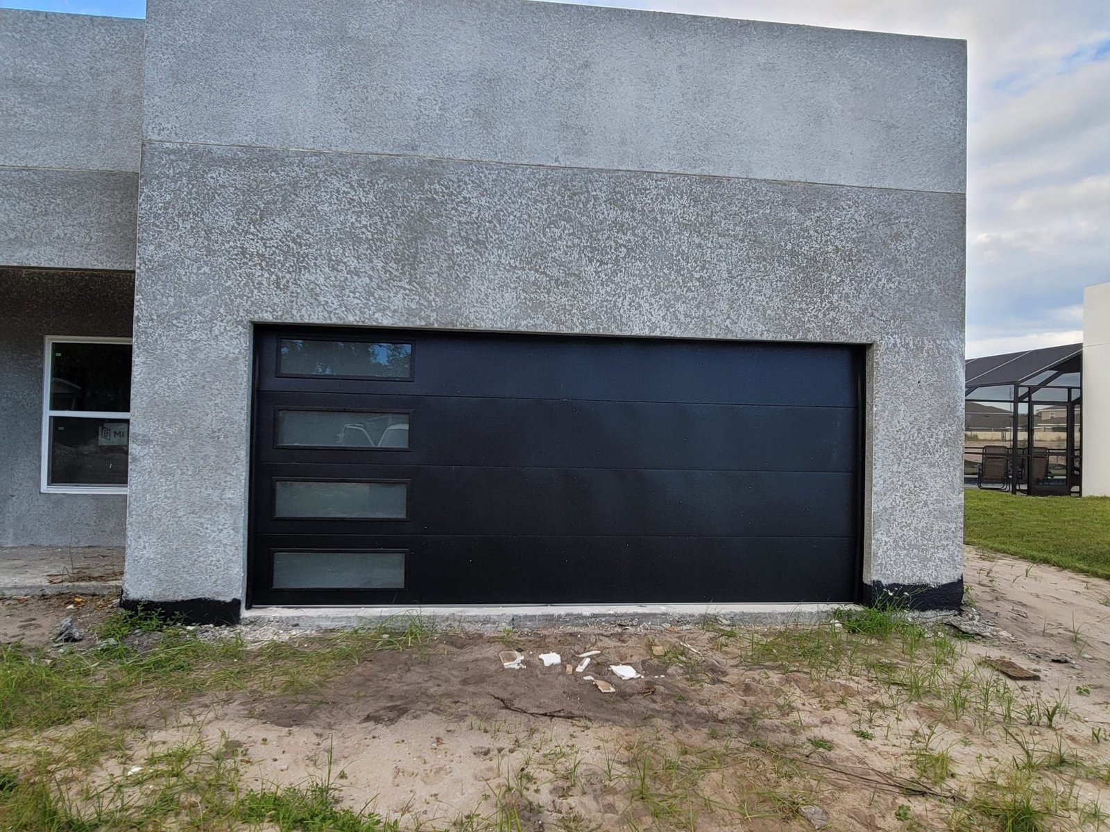 Modern flush black garage door with four frosted glass windows on the left side