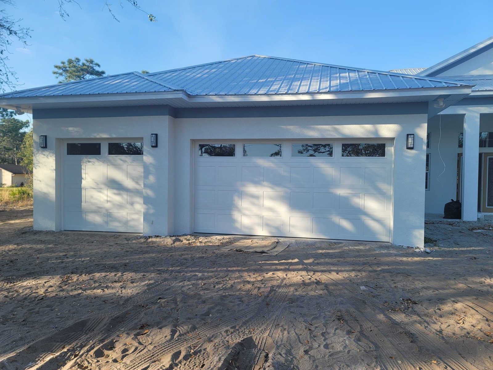 Newly installed white one-car and two-car garage doors with window tops on a new Florida home