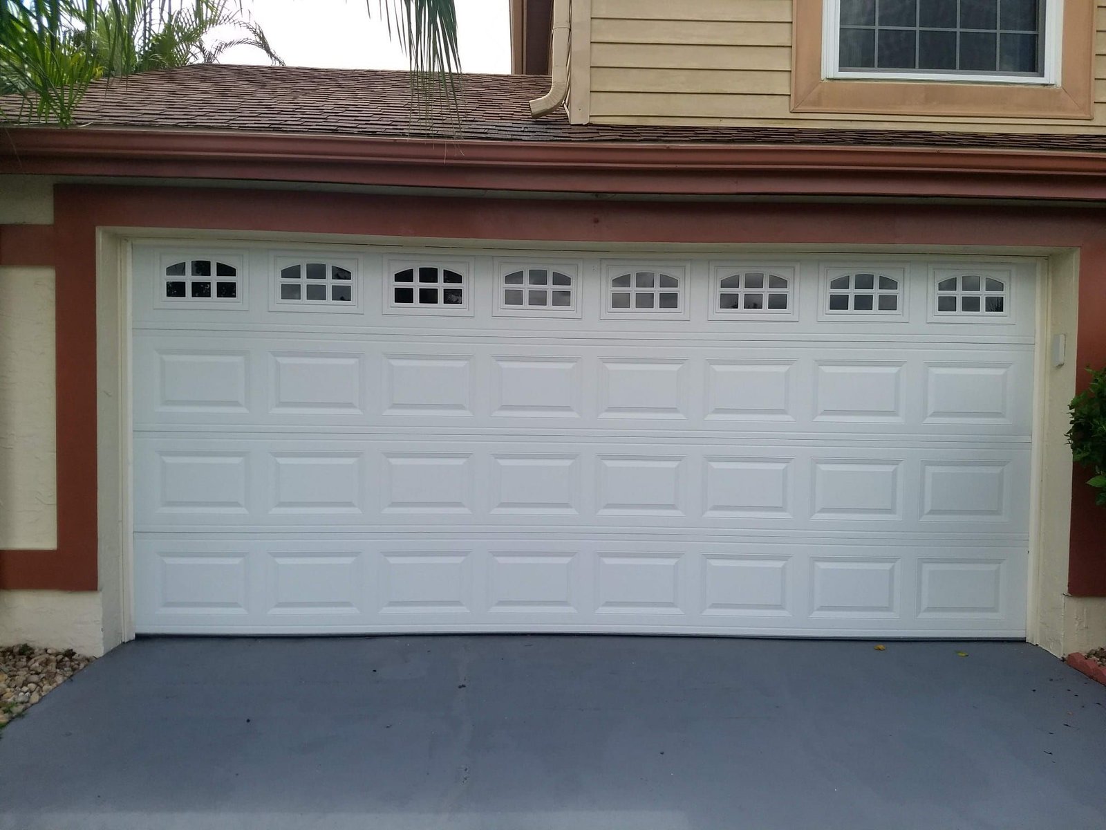 White raised-panel two-car garage door with arched window inserts on a Florida home